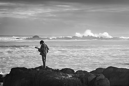 person near body of water in grayscale photography