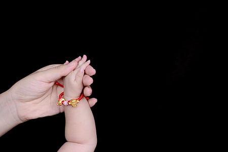 person holding baby's hand with black background