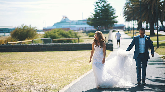 woman in white gown walking along with man in black