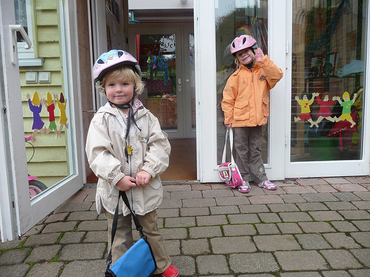 two children's wearing jackets and bicycle helmets