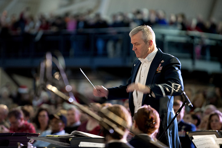 shallow focus photo of man in formal suit doing conducting