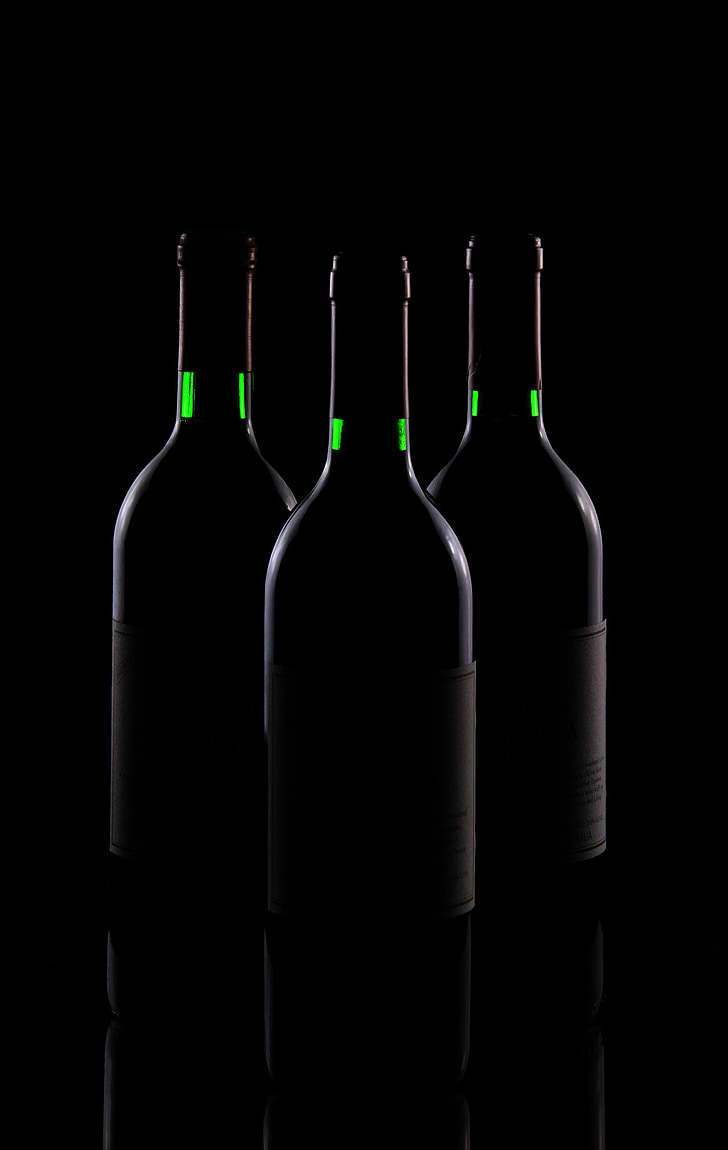 three white bottles on black surface