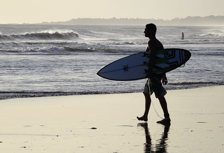 man holding surfboard on shore