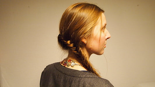 closeup photo of woman wearing gray top facing towards white wall