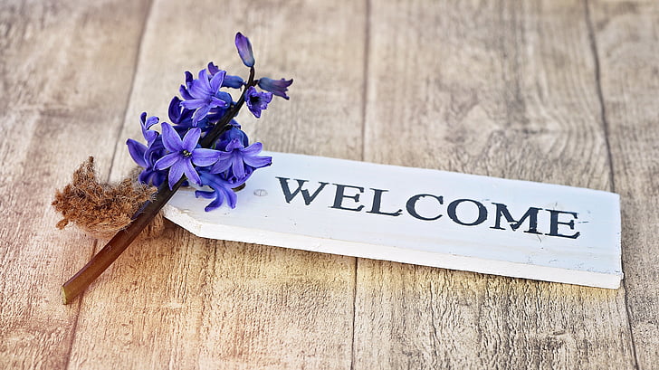 white wooden Welcome signage on brown wooden surface