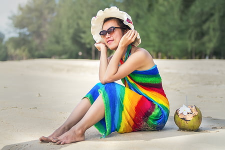 woman sitting on beach sand wearing brown sun hat
