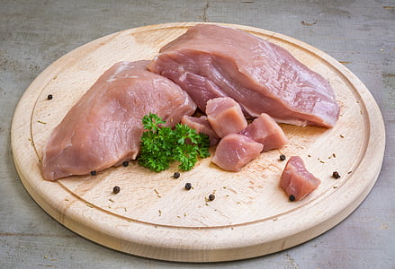 chicken breast and green parsley on round chopping board