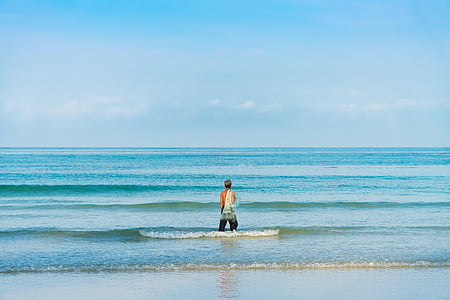 man standing near shoreline while water splashing