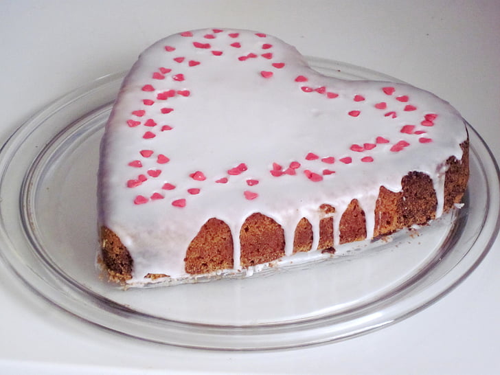 heart-shaped milk coated cake on top of clear glass plate