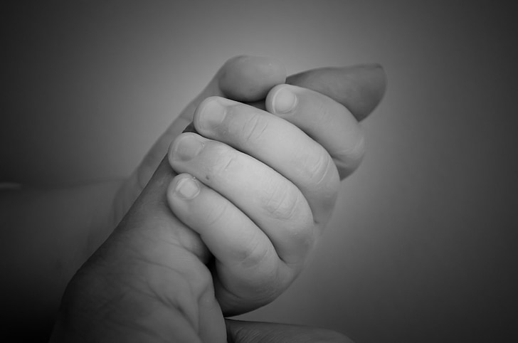 grayscale photo of baby holding index finger