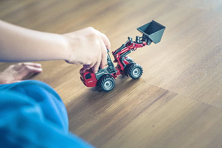 person holding red and gray heavy equipment toy