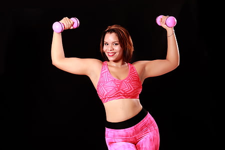 woman holding two pink dumbbells