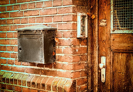 black mailbox mounted on brown brick wall