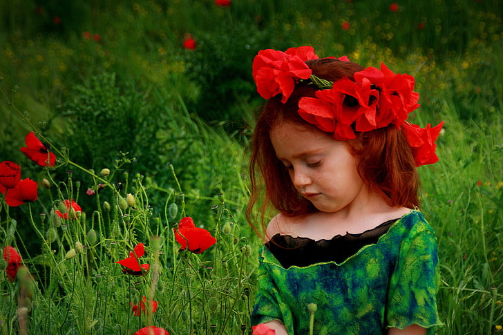 girl wearing black top standing beside red flowers