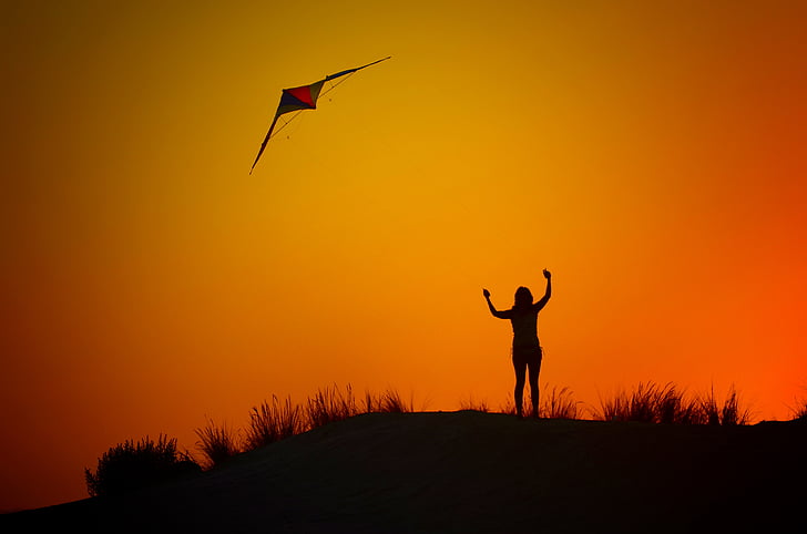 silhouette of woman flying kite