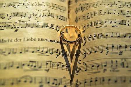 gold-colored band ring on opened musical book