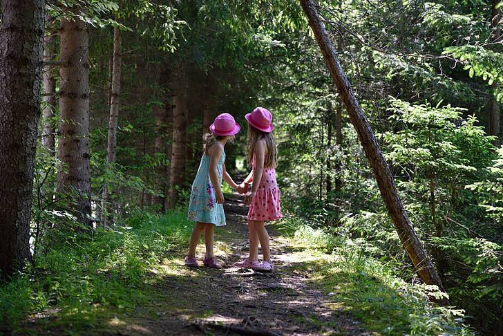 girls in pink and blue sleeveless dress holding hands