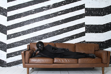 man lying on brown leather 3-seat sofa