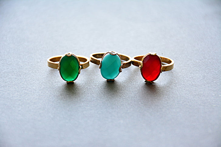 three gold-colored rings with three assorted-color gemstones