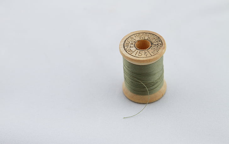 Spool of green thread and needle Stock Photo - Alamy