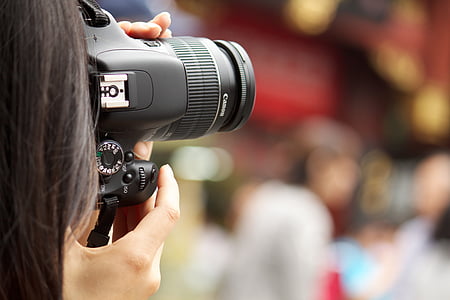 selective focus photography of woman holding DSLR camera