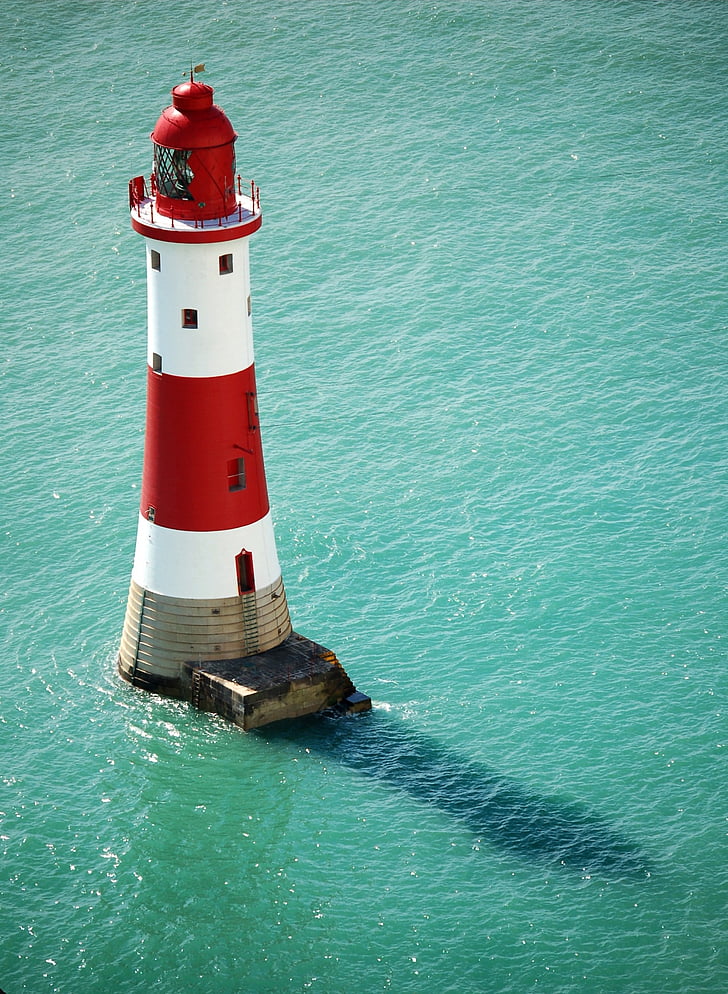 red and white lighthouse surrounded by body of water during daytime