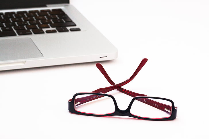 red and black framed eyeglasses beside MAcBook
