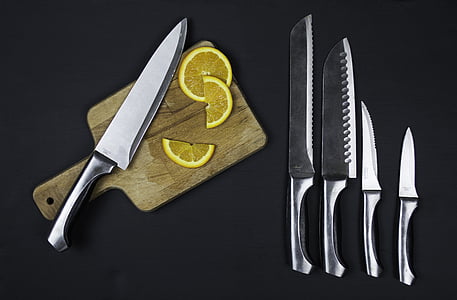 five stainless steel knives and sliced of orange fruit