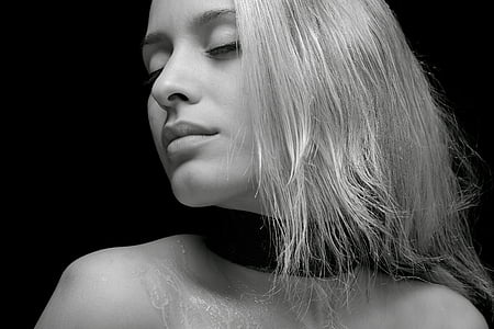 greyscale photo of woman with black top in black background