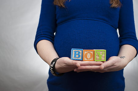 pregnant woman holding a BOY block in front of her tummy
