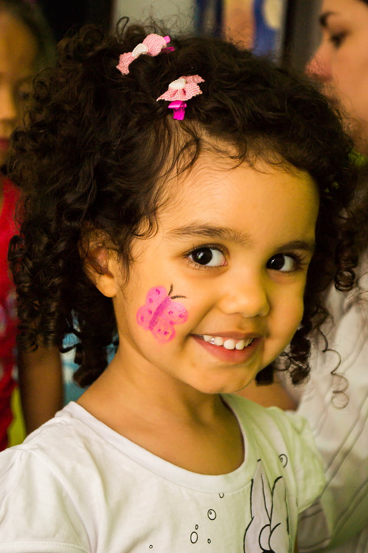 girl wearing white shirt with pink butterfly right cheek face paint