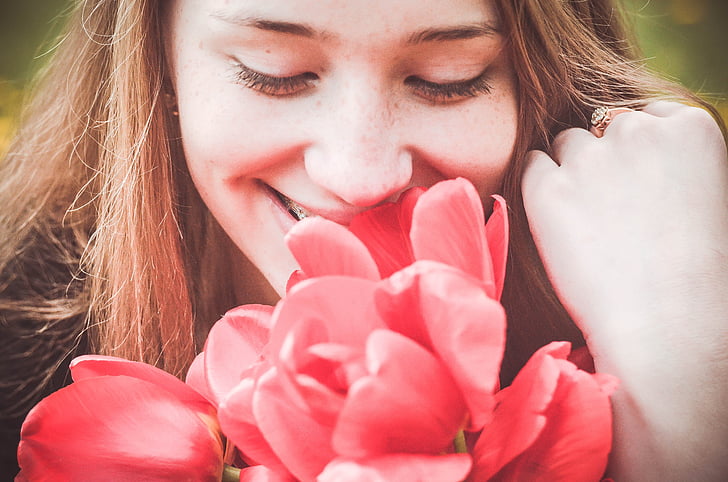 woman smelling red flowers