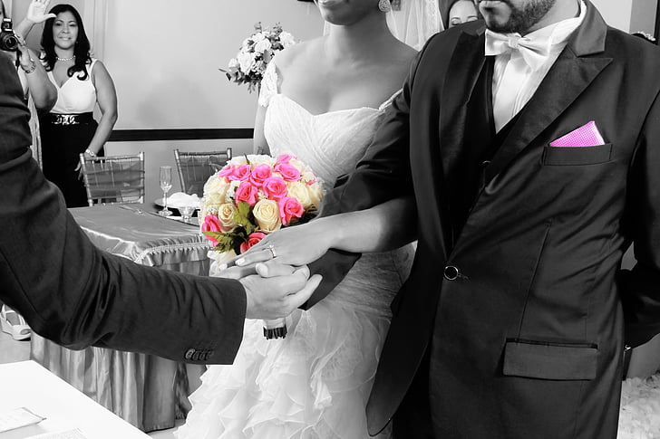 selective color photography of bride and groom holding white and pink rose flowers bouquet