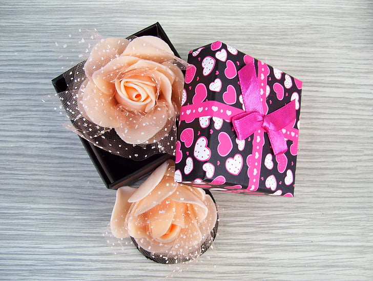 two peach-colored roses on black box