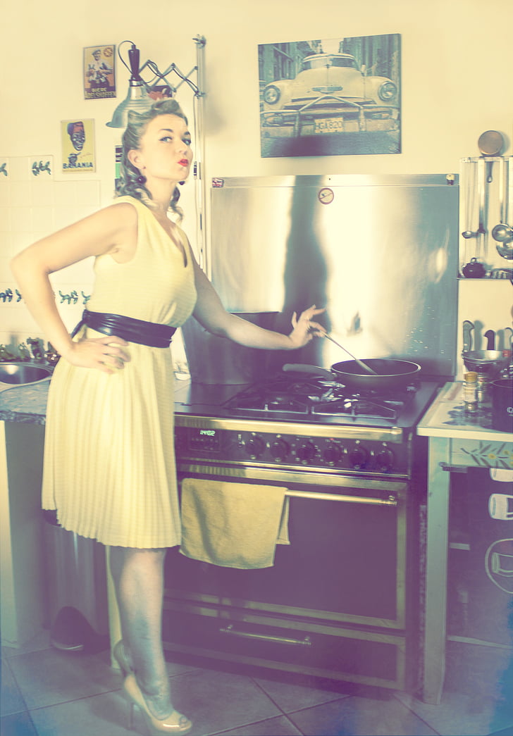 woman holding a gray ladle near gas range oven