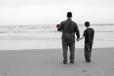 man and boy standing near seashore