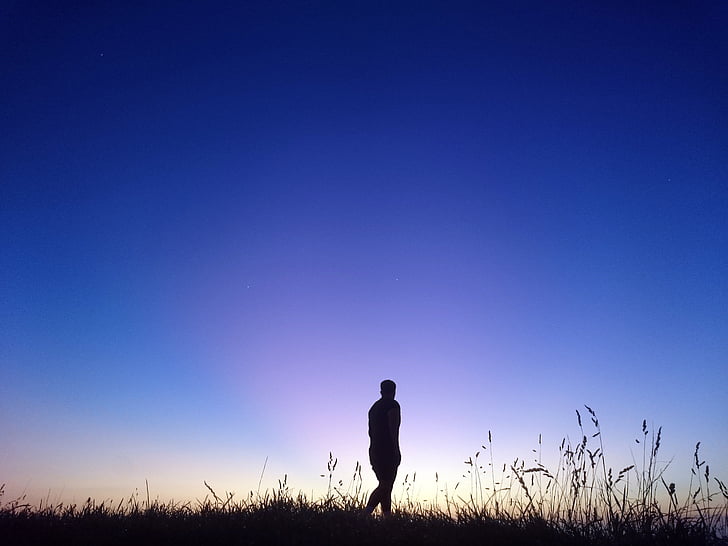 silhouette of person walking outdoor under blue sky