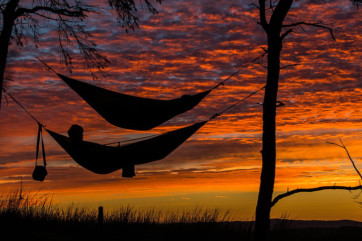 silhouette of a man on hammock during sunset