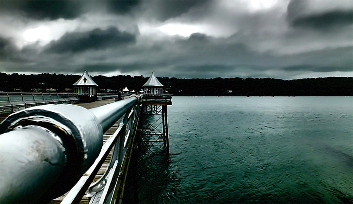 brown dock on sea under gray clouds