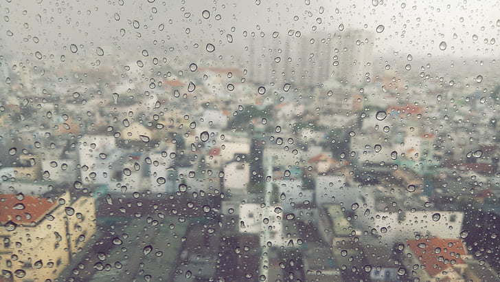 view through mirror of high rise buildings during rain