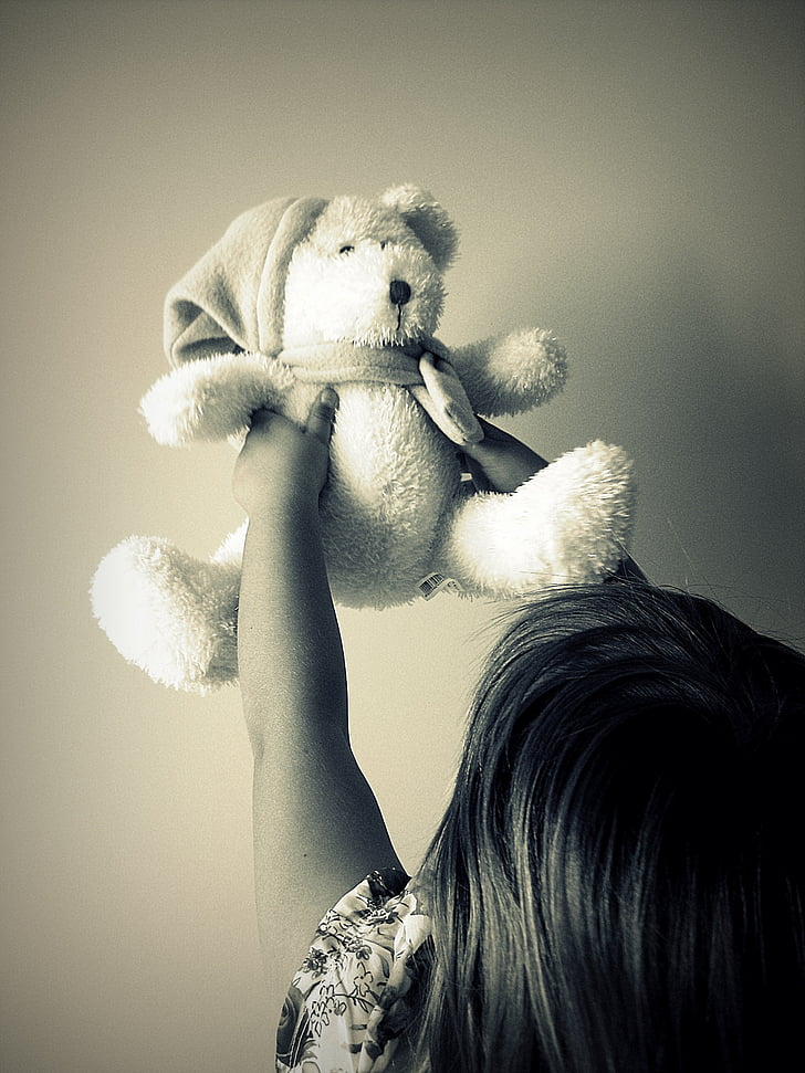 grayscale of toddler holding bear plush toy