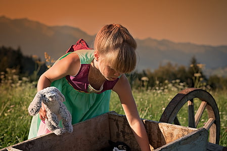 girl picking something on wheelbarrow