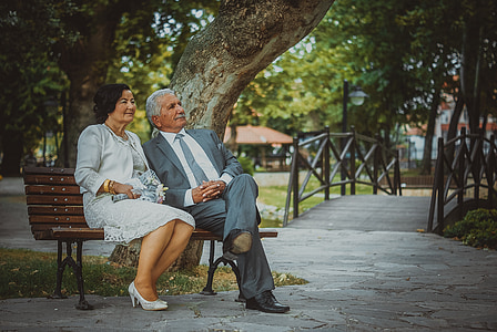man in gray suit jacket sitting on bench beside woman in white dress