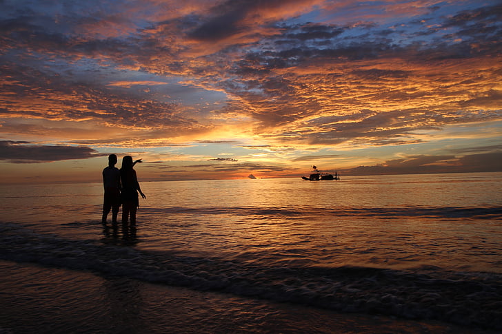 silhouette of two person near seashore during sunset