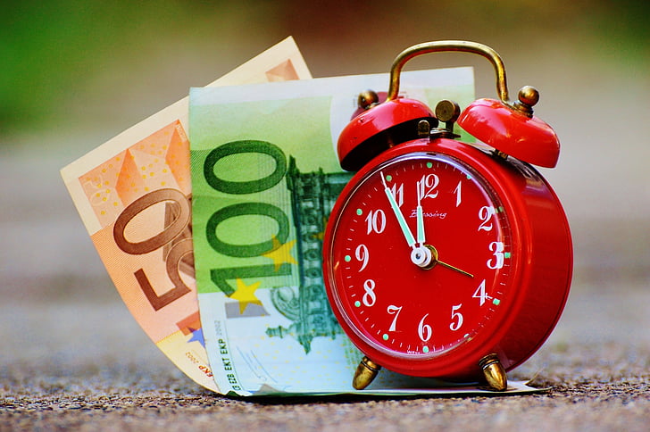 20 and 100 euro banknotes and red alarm clock with bell