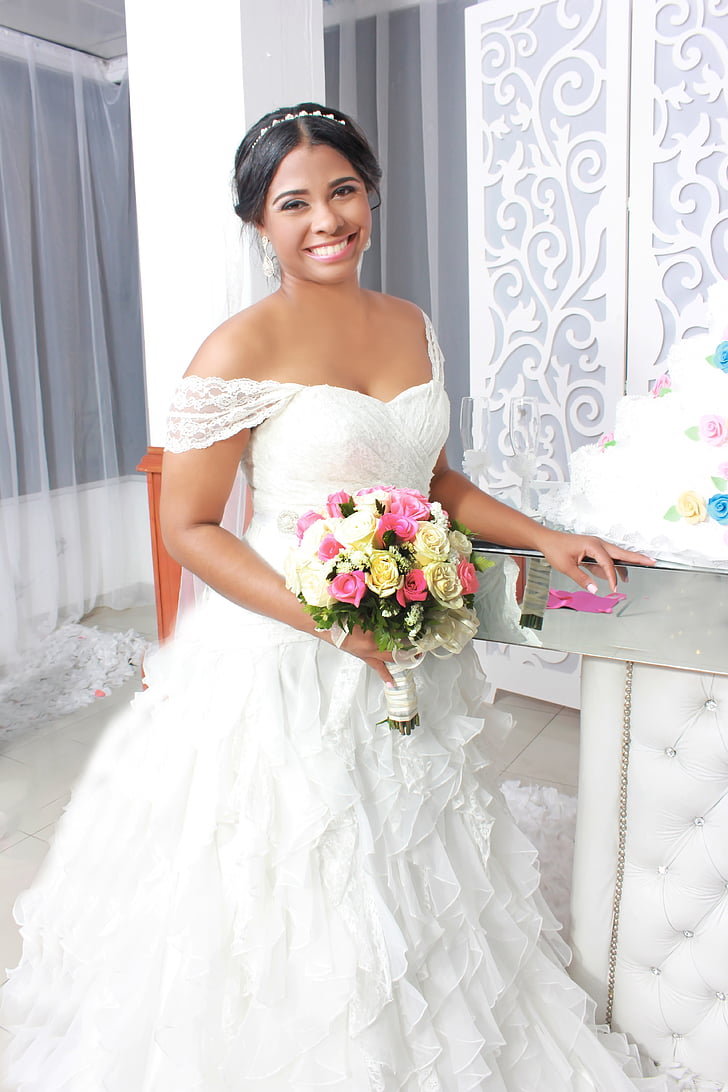 woman in white off-shoulder wedding dress holding flower bouquet