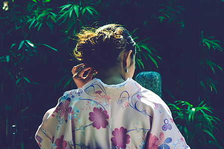 woman wearing floral top holding her ears