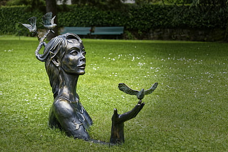woman with bird on hand statue on green grass field during daytime