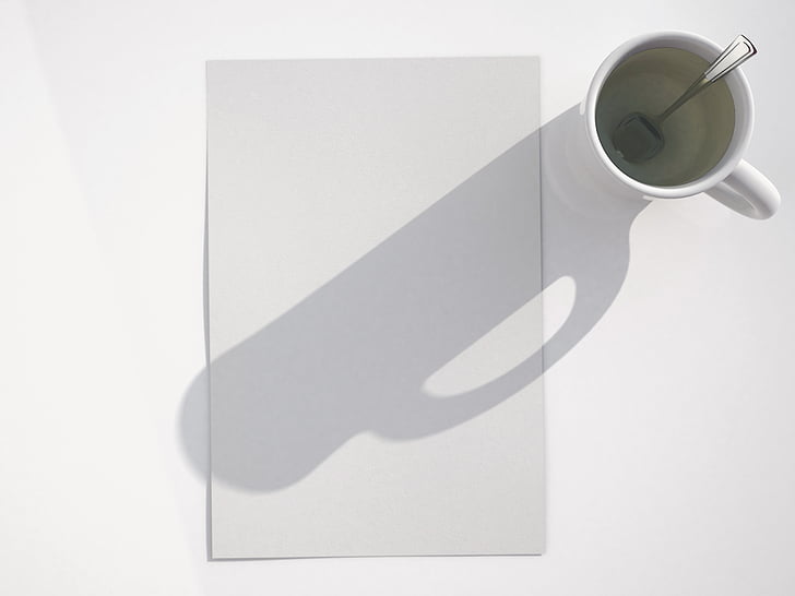 shadow of mug with tablespoon on white printer paper