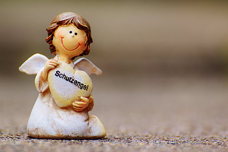 closeup photography of white angel figurine carrying heart